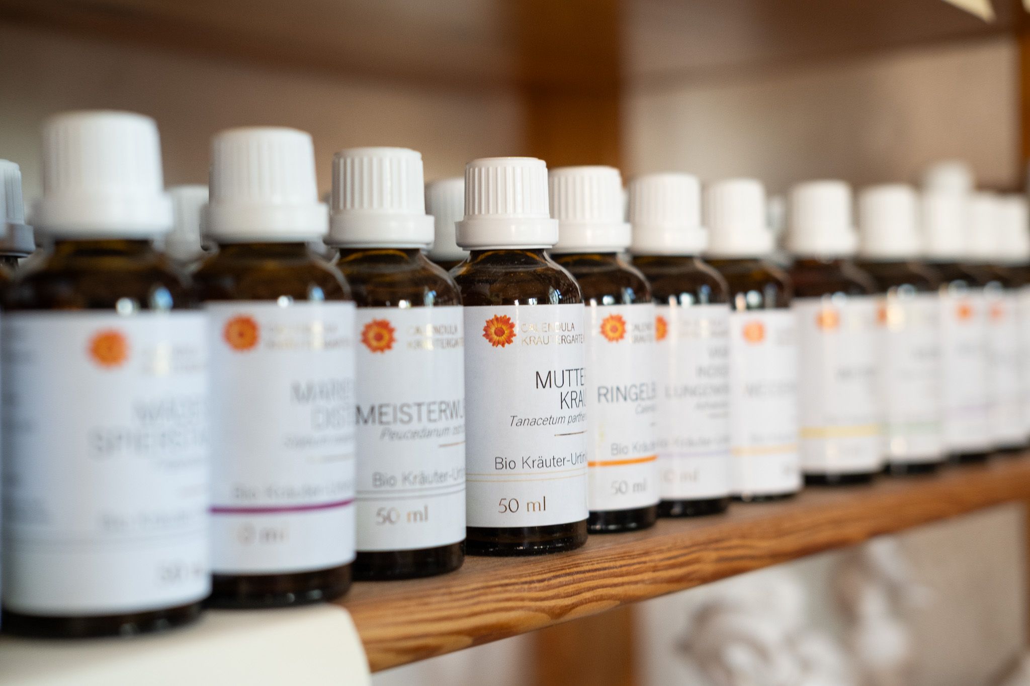 Fläschchen mit Bio-Kräuter-Urtinkturen des Calendula Kräutergartens im Holzregal